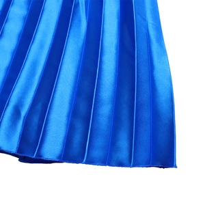 Detailed macro view of royal blue pleated skirt showing the shiny satin fabric texture