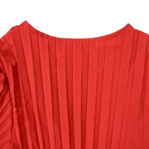 Détail macro du tissu plissé rouge de qualité avec texture verticale sur la robe