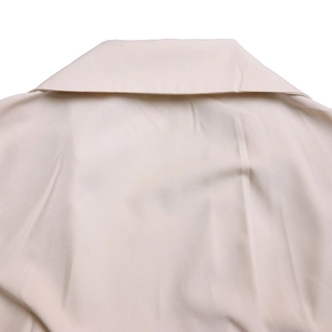 Detail view of a V-neck lapel collar on a beige pleated long-sleeve jumpsuit for women