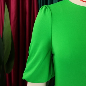 Detail of bright green puff sleeves and textured fabric on a slim-fit women dress