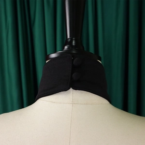 Close-up of black knitted collar accessory with dual buttons on a beige mannequin