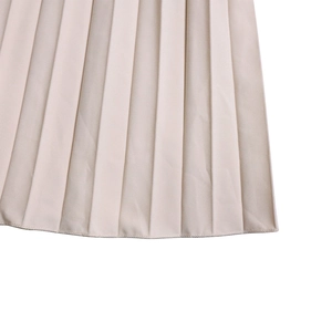 Detail view of beige pleated fabric showing precise stitching and hemline finish