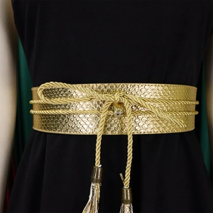 Detail of wide gold waist belt with metallic snake pattern texture and woven tassel ties