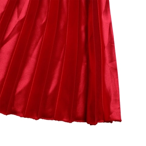 Detail of red pleated skirt showing the metallic satin texture and sharp accordion folds