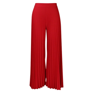 Detail of red high-waisted pleated wide-leg trousers with fine vertical pleats texture