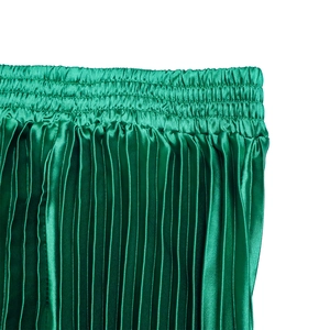 Close-up of bright green pleated satin skirt detail with elastic smocked waistline