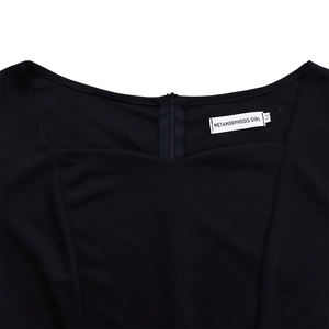 Détail d'une robe noire à col en U avec fermeture éclair invisible au dos et étiquette de marque
