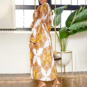 Detail of long sleeve pleated dress with orange and yellow paisley pattern textures