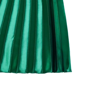 Macro detail of emerald green pleated satin skirt showing fine texture and hemline finish