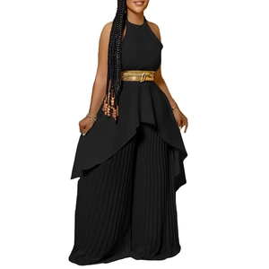 Detail of black halter top with irregular hem and pleated wide-leg pants with gold belt
