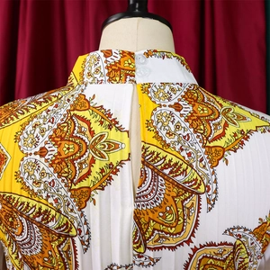 Detail of high collar pleated dress with orange paisley print and back button closure