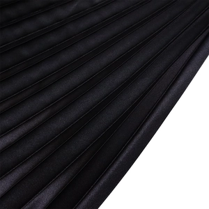 Detailed macro view of black pleated satin fabric with elegant light and shadow texture
