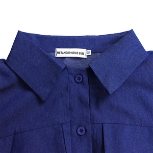 Détail du col pointu et de l'étiquette sur la robe longue en denim bleu à motifs
