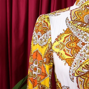 Detailed macro view showing the pleated texture and bohemian paisley print of the dress