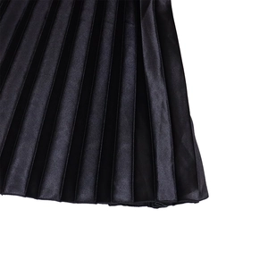 Detailed macro view of high-waist black pleated satin skirt fabric and vertical folds