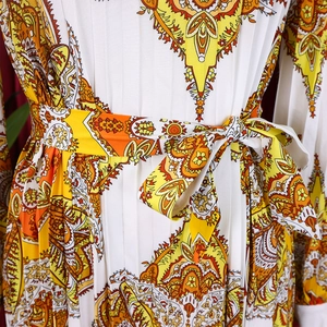 Detailed view of the waist tie and intricate paisley print on this pleated dress