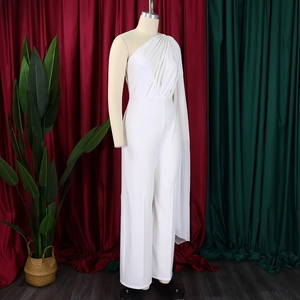 Detail of white one-shoulder jumpsuit featuring a dramatic draped cape sleeve and wide legs