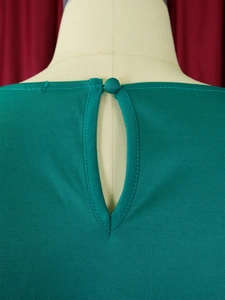 Detail of dark green textured top featuring a back teardrop cutout and fabric button closure