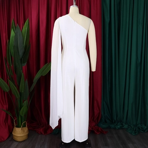 Detail of white one-shoulder jumpsuit featuring a long draping cape and wide leg cut