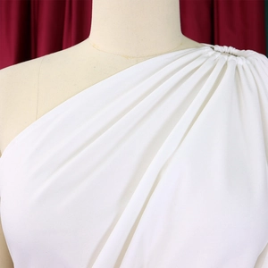Detail of elegant white one-shoulder dress with sophisticated pleated fabric draping