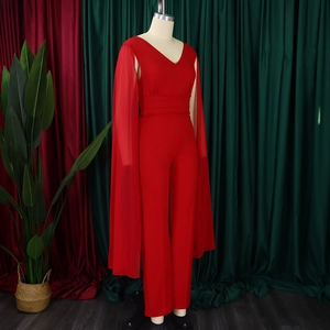 Détail d'une combinaison rouge à col en V avec manches cape et taille plissée sur mannequin