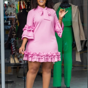 Detailed look at bow tie neckline and layered ruffle cuffs on a pink A-line dress