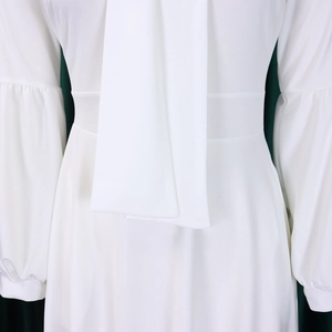Detail of white maxi dress with puff sleeves, high waist, and elegant neck tie bow