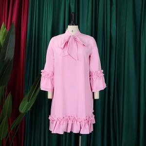 Detailed view of large bow tie neckline and layered ruffles on a pink long sleeve dress