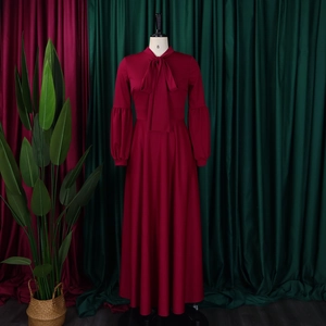 Detail of elegant red maxi dress with bow neckline and lantern sleeves on mannequin