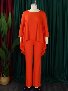 Detail of loose asymmetric high-low hem top and wide-leg pants in bright orange-red