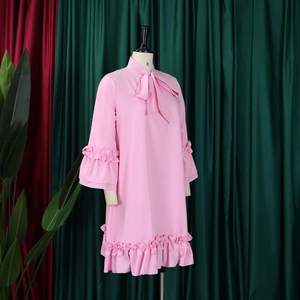 Detailed close-up of pink long sleeve dress featuring a bow neckline and ruffled hem