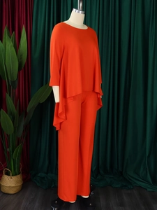 Detailed view of the bright orange asymmetrical long sleeve top and wide-leg pant set