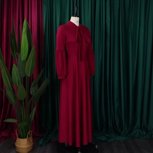 Detail of burgundy long-sleeve maxi dress with bow neckline and puff lantern sleeves