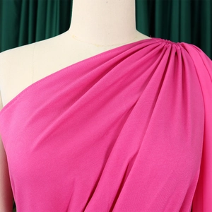 Detail of elegant one-shoulder magenta dress featuring sophisticated pleated shoulder design