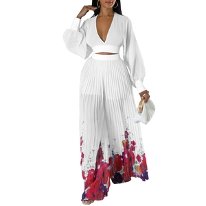 Detail of white pleated chiffon top with deep V-neck and floral print wide leg trousers