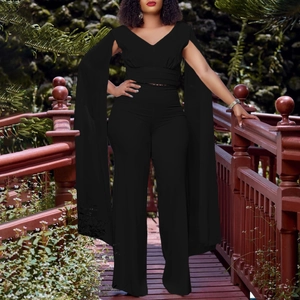 Détail du haut à col en V avec manches cape et pantalon large noir en tissu fluide