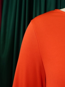 Detail of vibrant orange knit fabric showing high-quality stitching and texture