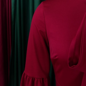 Close-up of elegant ruffled cuffs on a burgundy long-sleeved dress with smooth fabric