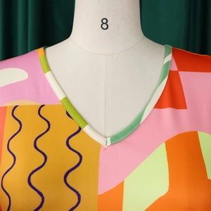 Détail du col en V présentant des motifs géométriques colorés et des textures ondulées