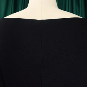 Détail de l'encolure en V d'un haut noir exposé sur un mannequin de couleur beige