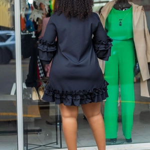 Detail view of the layered ruffle hem and bell sleeves on a black A-line dress
