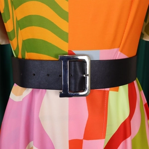 Détail d'une large ceinture en cuir noir avec boucle en métal argenté en D sur une robe