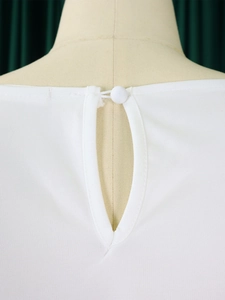 Close-up of white elegant top featuring keyhole back with matching button closure