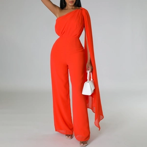 Detail of a bright orange one-shoulder jumpsuit featuring a long flowing chiffon cape