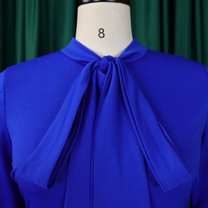 Detail of royal blue bow tie neck with refined fabric texture on dress bodice