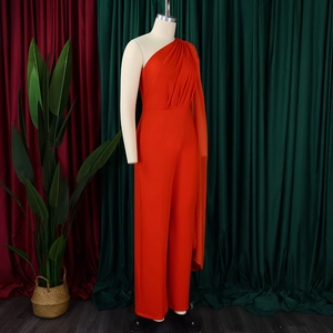 Detail of orange one-shoulder jumpsuit featuring elegant pleats and long side sash