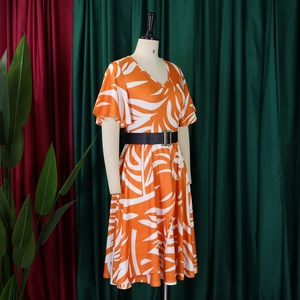 Détail de la robe mi-longue à col en V avec imprimé feuilles orange et ceinture noire