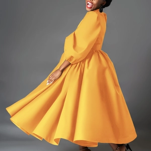 Dynamic detail of bright yellow A-line dress featuring vintage puff sleeves and large hem