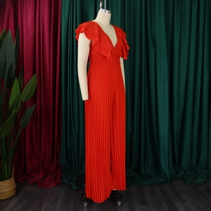 Détail d'une combinaison rouge-orange avec col en V et pantalon large plissé