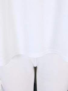 Detailed close-up showing the double-stitched hem finish on a white knit tunic top